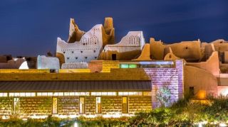 National Museum of Saudi Arabia and Al Murabba Palace Afternoon Tour A nighttime view of historical buildings in Riyadh, Saudi Arabia, illuminated with warm lights, showcasing the blend of traditional architecture with modern elements.