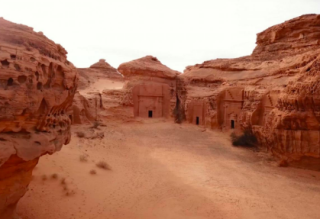 Saudi Arabian Highlights and Secrets Tour into the Wild North and Rock Civilizations This image shows rock-cut tombs in Mada'in Saleh, Saudi Arabia, set within a sandy desert landscape framed by unique rock formations.